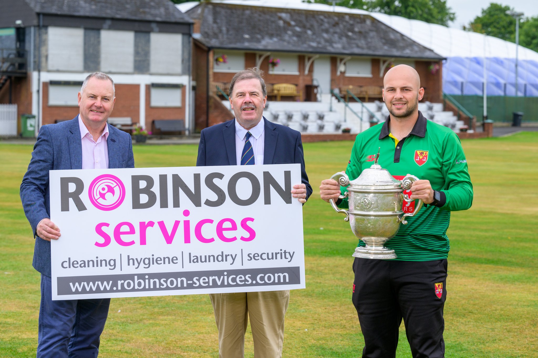 Lisburn captain Callum Atkinson alongside David Robinson of sponsor Robinson Services and NCU president Roger Bell